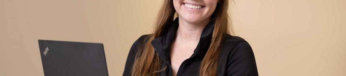 Nursing student smiling while holding laptop