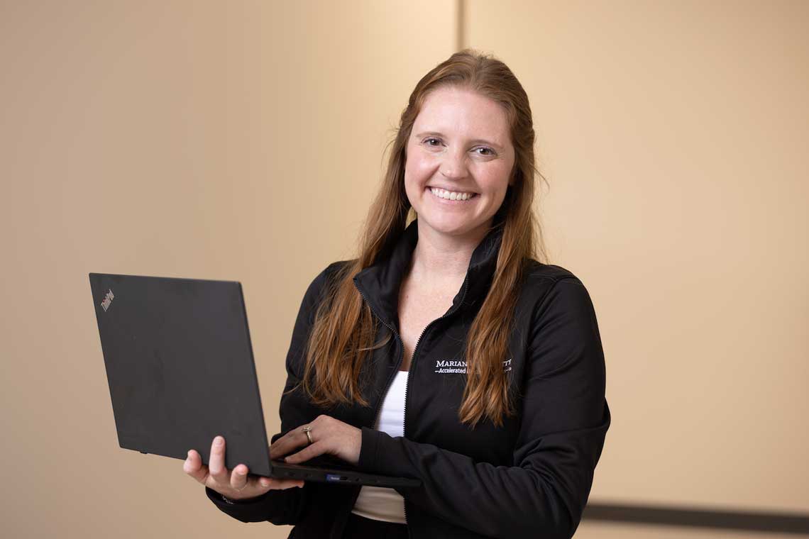 Nursing student smiling while holding laptop